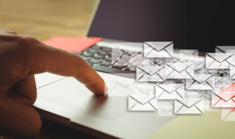 Finger pressing a laptop touchpad with many email icons appearing, illustrating email overload