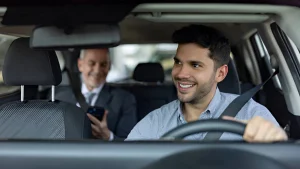 Driver holds steering wheel while passenger in back checks phone — scene relates to "Create a Lyft Account Without a Phone Number."