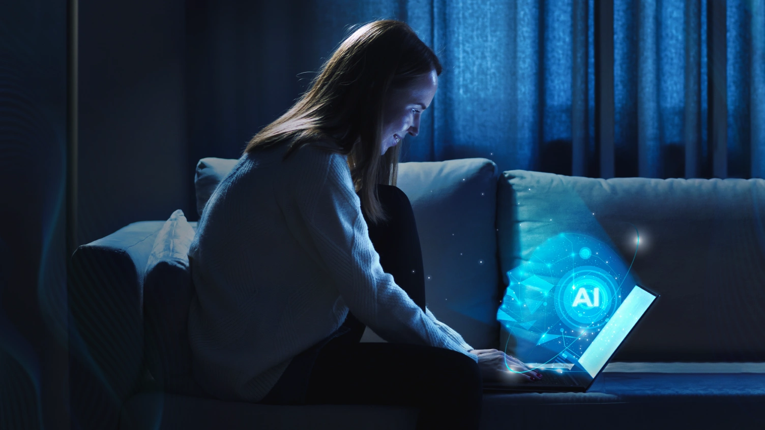 This picture displays a woman sitting on a couch using a laptop.