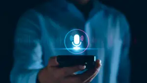 A person holding a smartphone with a glowing microphone icon and sound waves appearing above the screen.