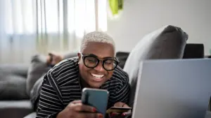 A man smiling while he uses feature of unified messaging in his smartphone.